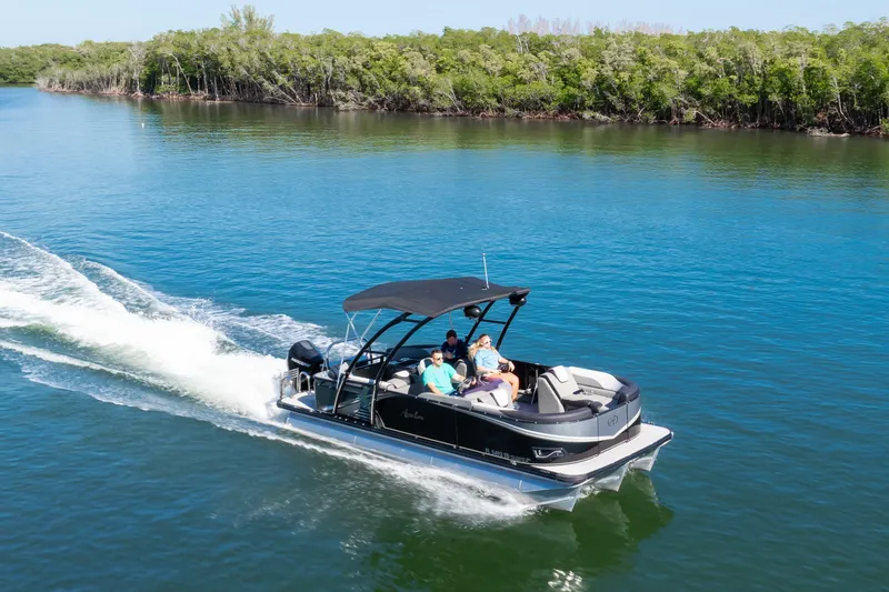 Slide: The Image of 2021 Avalon LSZ Quad Lounger boat cruising on a serene lake with lush greenery. - 15