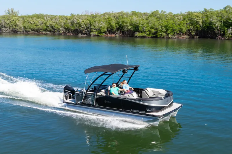 Slide: The Image of 2021 Avalon LSZ Quad Lounger 24' pontoon boat cruising on a serene lake. - 16