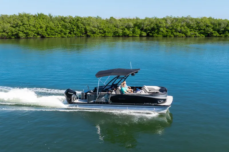 Slide: The Image of 2021 Avalon LSZ Quad Lounger boat cruising on a serene lake with lush greenery. - 18
