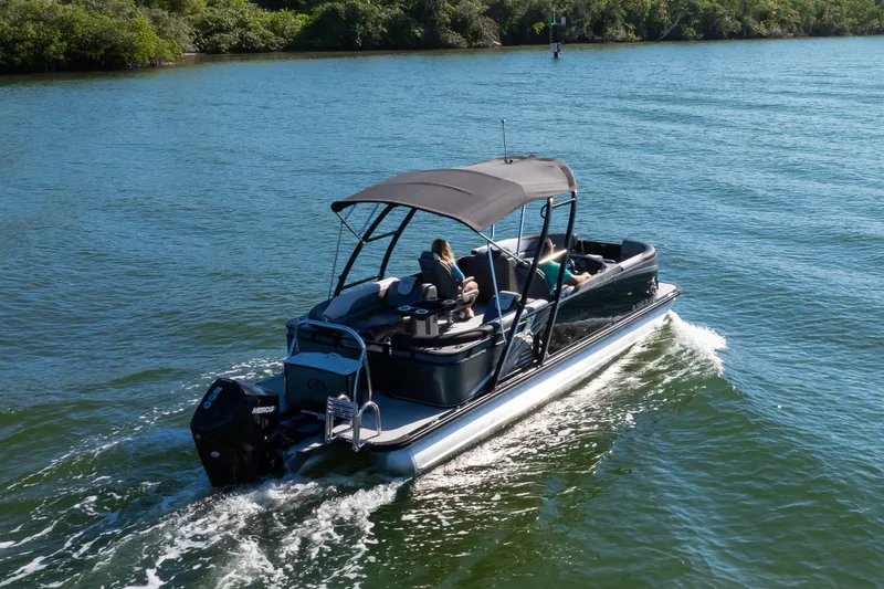 Slide: The Image of 2021 Avalon LSZ Quad Lounger 24' pontoon boat cruising on a scenic lake. - 2