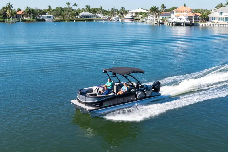 Slide: The Image of 2021 Avalon LSZ Quad Lounger cruising on a serene lake with waterfront homes. - 20