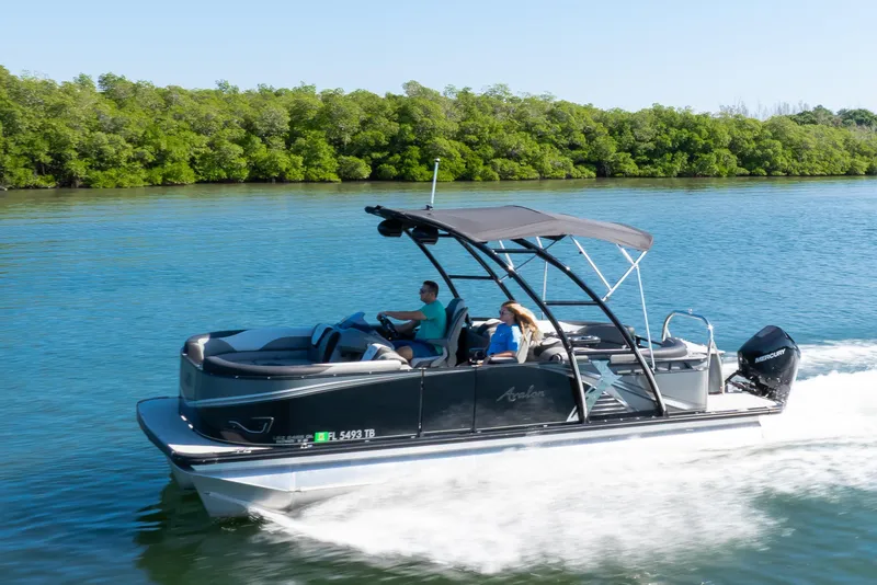 Slide: The Image of 2021 Avalon LSZ Quad Lounger 24' pontoon boat cruising on a scenic waterway. - 24