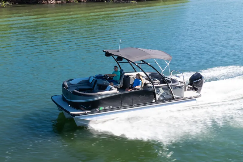 Slide: The Image of 2021 Avalon LSZ Quad Lounger 24' pontoon boat cruising on a serene lake. - 26