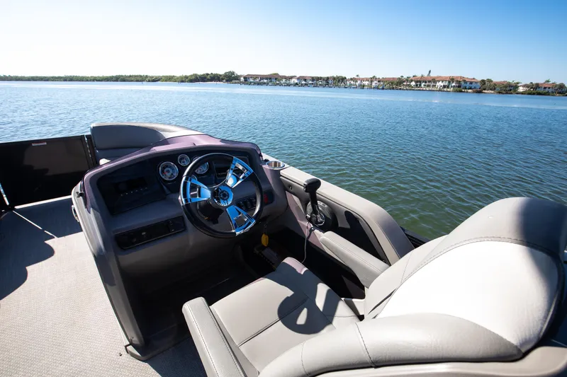 Slide: The Image of 2021 Avalon LSZ Quad Lounger boat interior with steering wheel on a sunny lake. - 30
