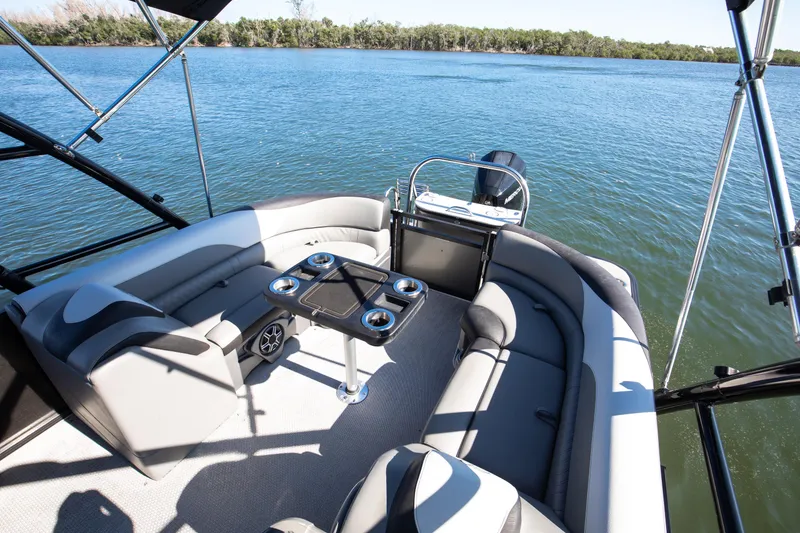 Slide: The Image of 2021 Avalon LSZ Quad Lounger boat interior with seating and table on a lake. - 36