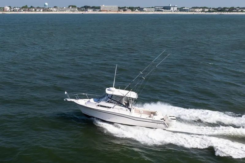 Slide: The Image of 1997 Grady-White Marlin 300 boat cruising on open water near coastline. - 12