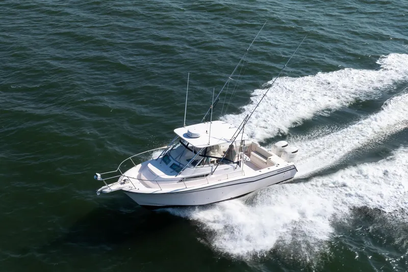 Slide: The Image of 1997 Grady-White Marlin 300 boat cruising on open water, creating a wake. - 13