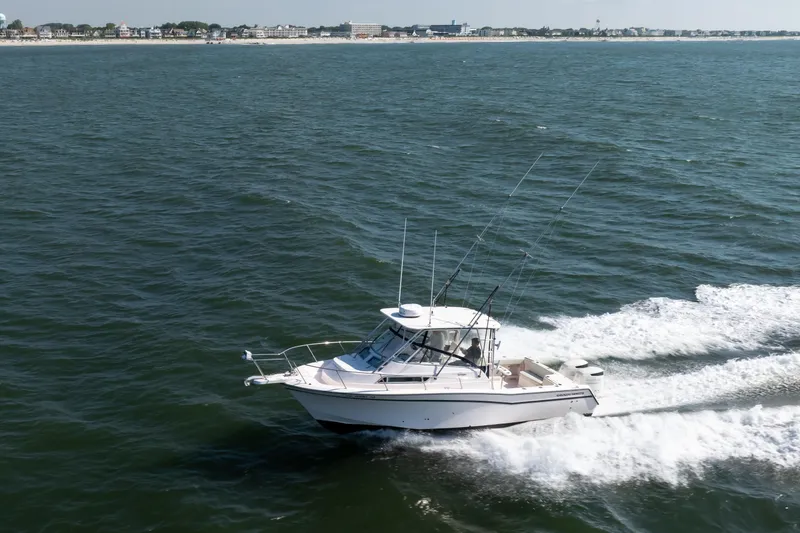 Slide: The Image of 1997 Grady-White Marlin 300 boat cruising on open water near coastline. - 16