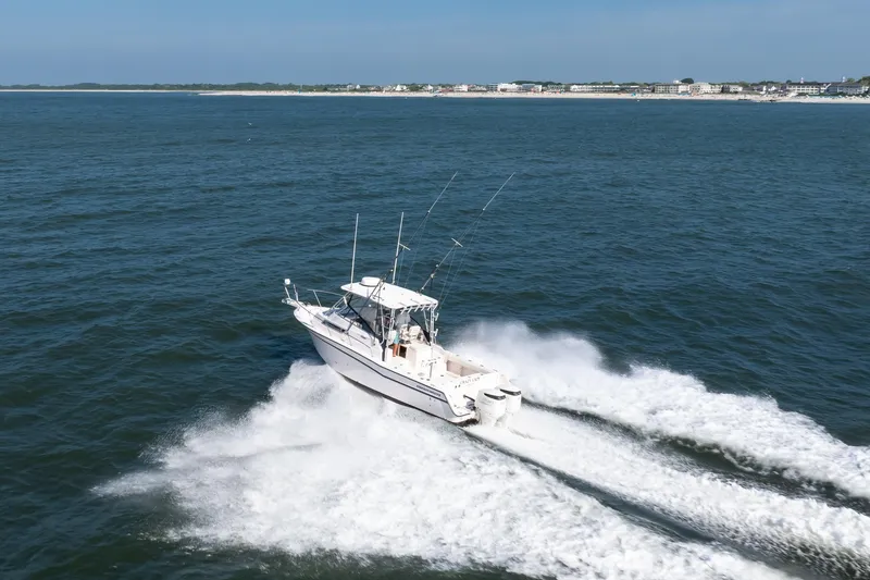 Slide: The Image of 1997 Grady-White Marlin 300 boat cruising on open water near coastline. - 19