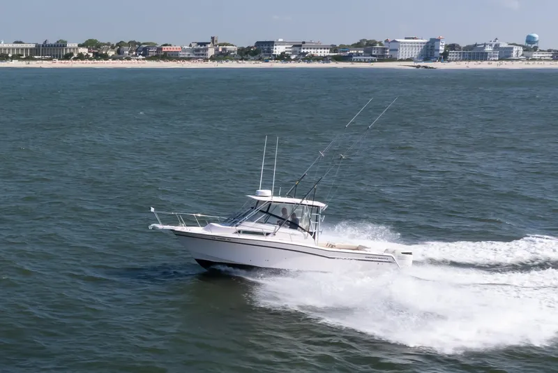 Slide: The Image of 1997 Grady-White Marlin 300 boat cruising on ocean near coastal cityscape. - 20