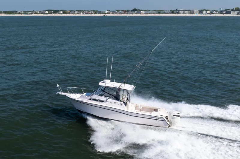 Slide: The Image of 1997 Grady-White Marlin 300 boat cruising on open water near coastline. - 21