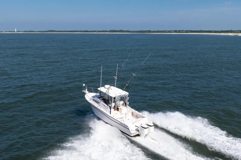 Slide: The Image of 1997 Grady-White Marlin 300 boat cruising on open water, with fishing rods visible. - 23