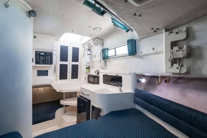 Slide: The Image of Interior of 1997 Grady-White Marlin 300 boat, featuring compact kitchen and seating area. - 65