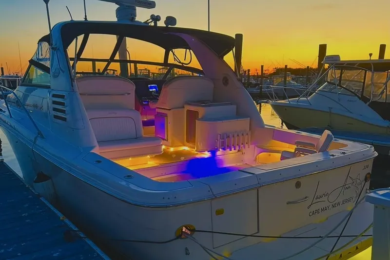 The Image of 1998 Sea Ray 340 Amberjack boat docked at sunset with illuminated interior. - 0