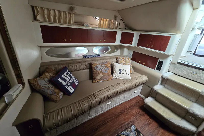 Slide: The Image of 1998 Sea Ray 340 Amberjack interior with cozy seating, decorative pillows, and wooden cabinetry. - 20