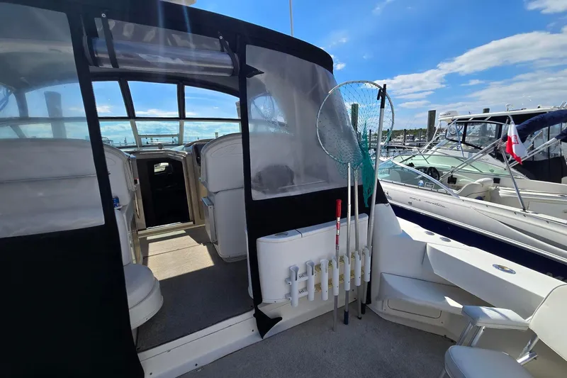 Slide: The Image of 1998 Sea Ray 330 Express boat interior with fishing gear, docked under a clear blue sky. - 12