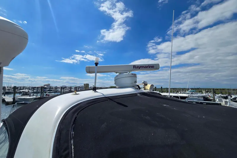 Slide: The Image of 1998 Sea Ray 330 Express with Raymarine radar, docked under a clear blue sky. - 15