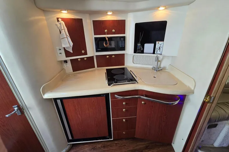 Slide: The Image of 1998 Sea Ray 330 Express yacht kitchen with stove, sink, and wooden cabinetry. - 25