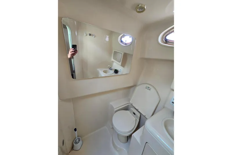 Slide: The Image of Bathroom interior of 1998 Sea Ray 330 Express boat, featuring toilet and mirror. - 32