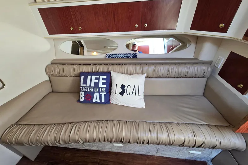 Slide: The Image of 1998 Sea Ray 330 Express cabin interior with cushioned seating and decorative pillows. - 35