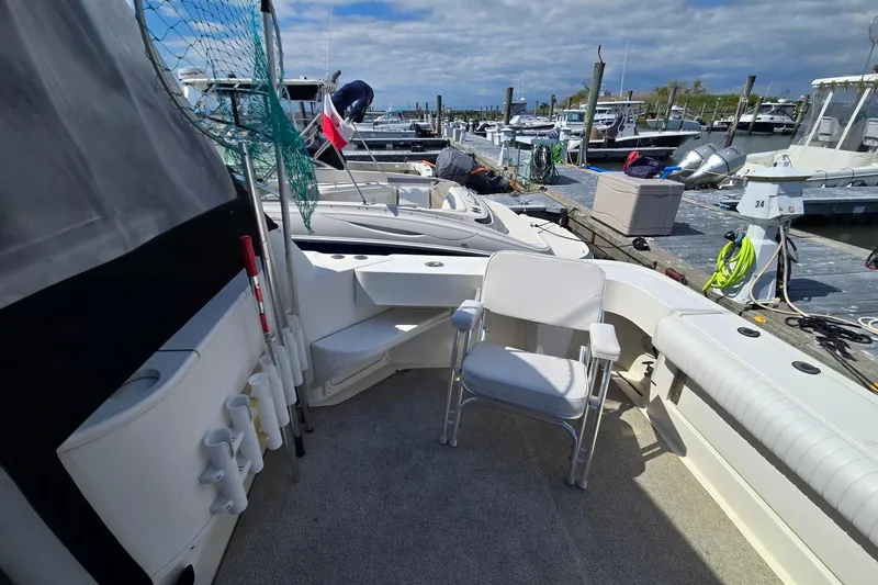 Slide: The Image of 1998 Sea Ray 330 Express boat interior with seating, docked at marina under cloudy sky. - 40