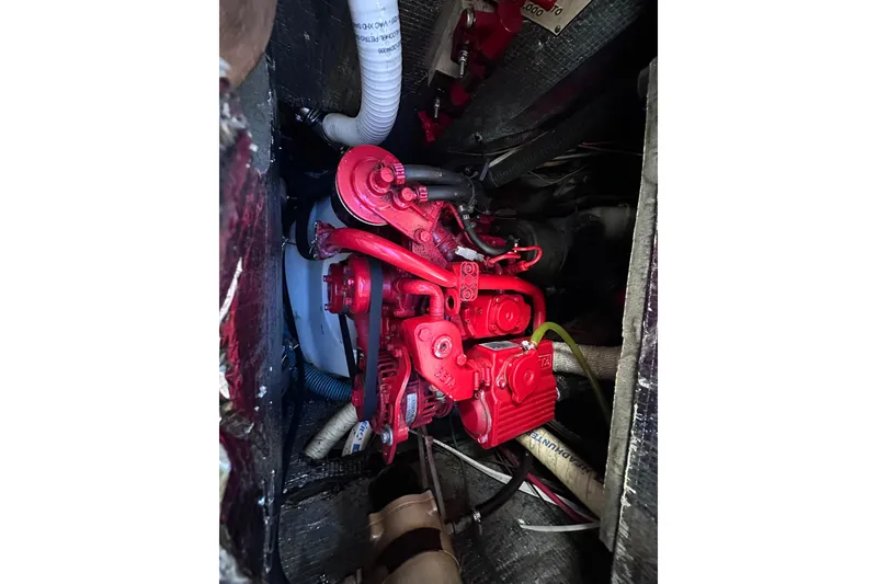 Slide: The Image of Red engine inside a 1975 Cape Dory 28 boat, surrounded by hoses and cables. - 27