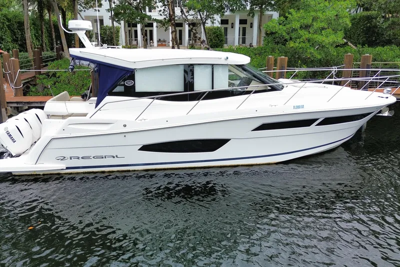The Image of 2021 Regal 38 XO boat docked on calm water, featuring sleek design and Yamaha engines. - 0