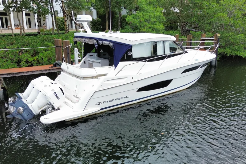 Slide: The Image of 2021 Regal 38 XO boat docked on calm water, featuring Yamaha engines. - 15