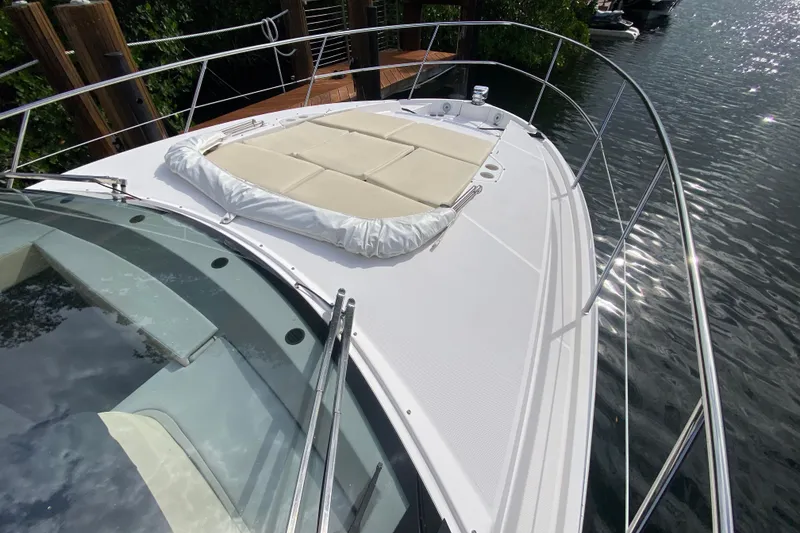 Slide: The Image of 2021 Regal 38 XO yacht with sunpad on deck, docked by water. - 17