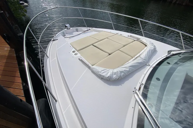 Slide: The Image of 2021 Regal 38 XO yacht with sunbathing deck, docked by the water. - 18