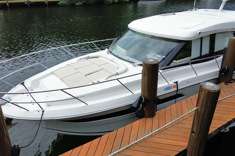 Slide: The Image of 2021 Regal 38 XO boat docked on a wooden pier by the water. - 2