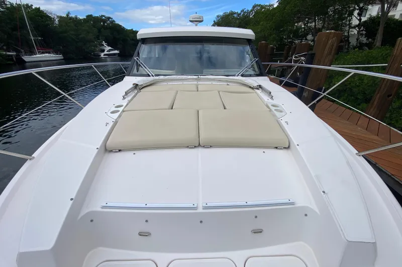 Slide: The Image of 2021 Regal 38 XO yacht with sunpad, docked by lush greenery. - 20