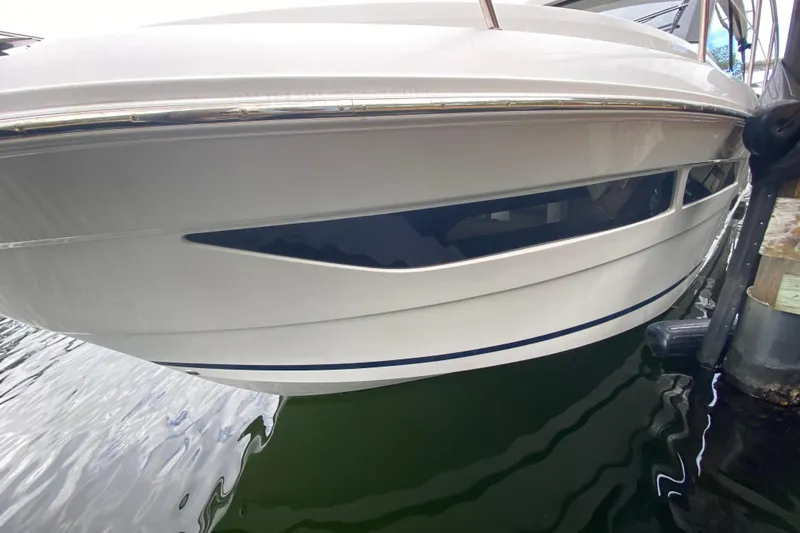 Slide: The Image of 2021 Regal 38 XO boat hull close-up, docked on calm water. - 22