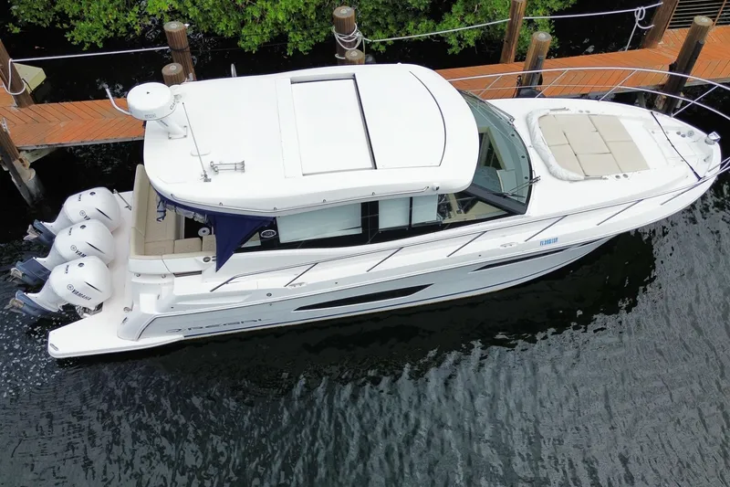 Slide: The Image of 2021 Regal 38 XO yacht docked, featuring triple Yamaha outboard engines and sleek design. - 5