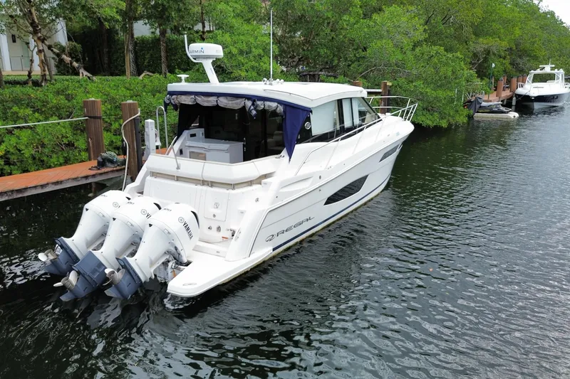 Slide: The Image of 2021 Regal 38 XO yacht docked on a serene waterway with lush greenery. - 58