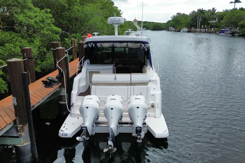 Slide: The Image of 2021 Regal 38 XO boat docked on a serene waterway with lush greenery. - 60