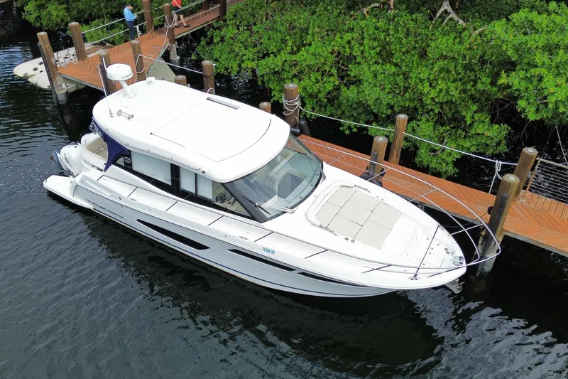Slide: The Image of 2021 Regal 38 XO yacht docked by lush greenery and wooden pier. - 7