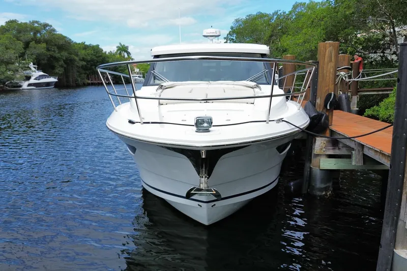Slide: The Image of 2021 Regal 38 XO yacht docked by a wooden pier, surrounded by lush greenery. - 8