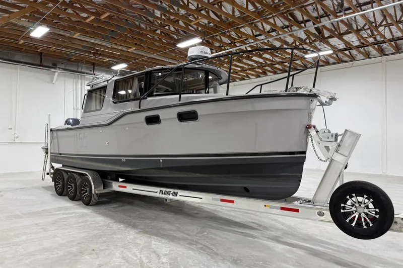 The Image of 2024 Ranger Tugs R-27 boat on trailer in warehouse setting. - 0