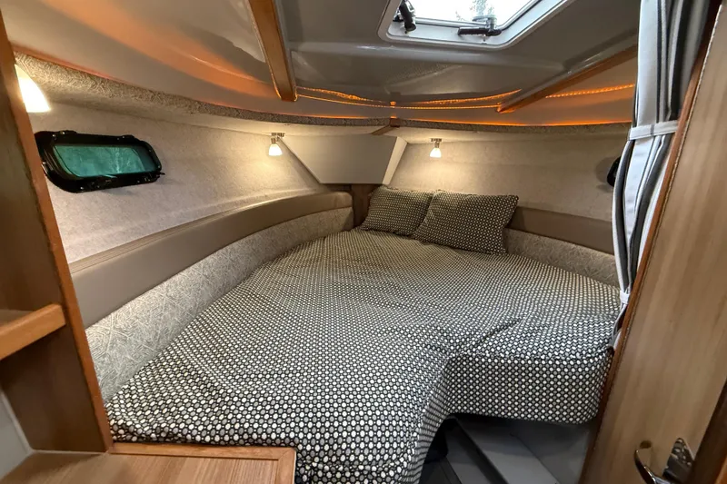 Slide: The Image of 2024 Ranger Tugs R-27 cabin interior with cozy bed and ambient lighting. - 10