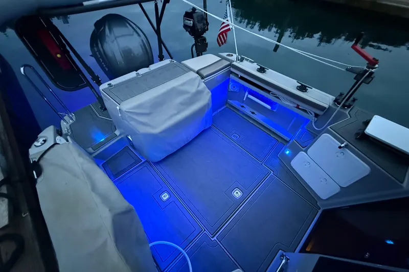 Slide: The Image of 2024 Ranger Tugs R-27 boat deck with blue LED lighting and covered equipment. - 16
