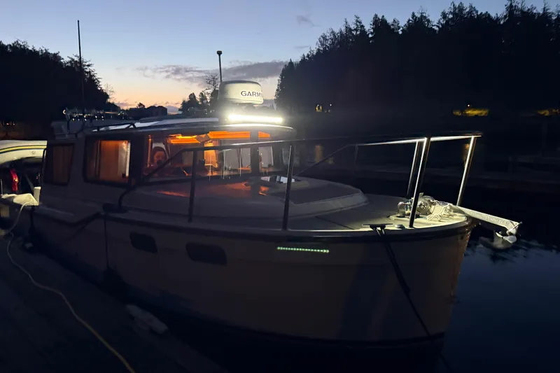 Slide: The Image of 2024 Ranger Tugs R-27 boat docked at sunset with illuminated cabin. - 17