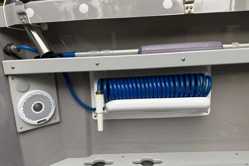 Slide: The Image of 2024 Ranger Tugs R-27 boat interior with coiled hose, speaker, and storage compartment. - 20