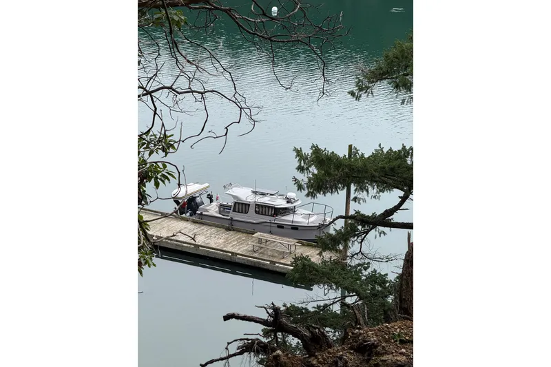 Slide: The Image of 2024 Ranger Tugs R-27 docked on serene water, surrounded by lush greenery. - 3