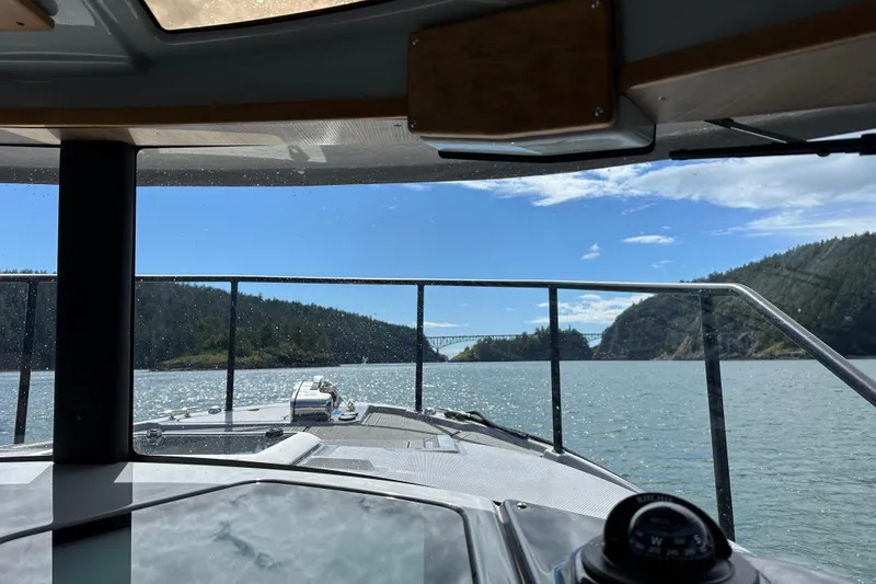 Slide: The Image of View from 2024 Ranger Tugs R-27 boat, navigating scenic waters with bridge and hills. - 5
