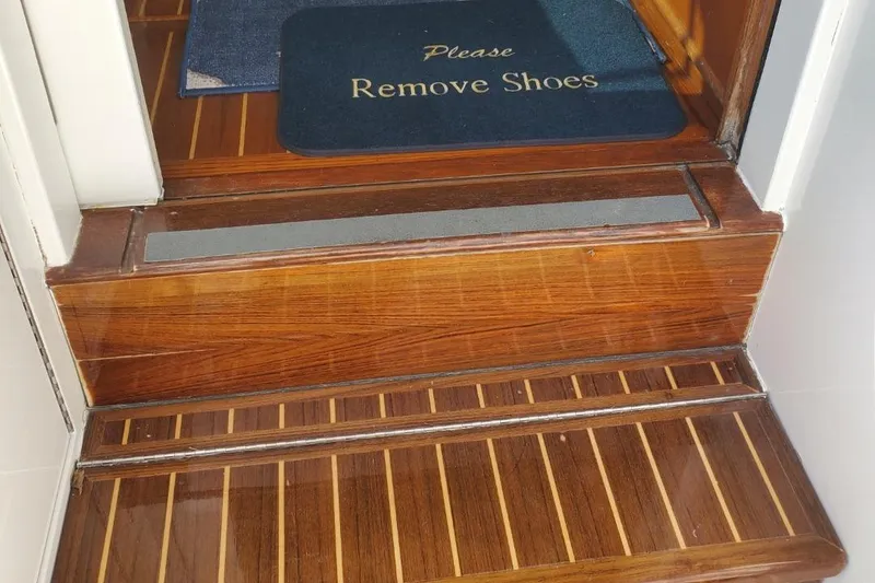 Slide: The Image of Wooden steps with "Please Remove Shoes" mat on 1988 Post 46 Sportfish boat. - 33