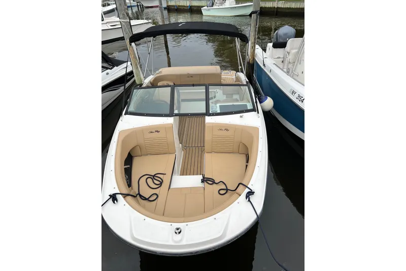 Slide: The Image of 2021 Sea Ray SPX 190 boat docked, featuring tan seating and black canopy. - 2