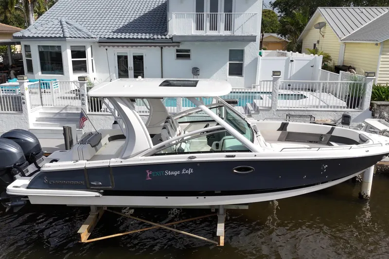 The Image of 2023 Chaparral 300 OSX boat docked by a waterfront house with a pool. - 0