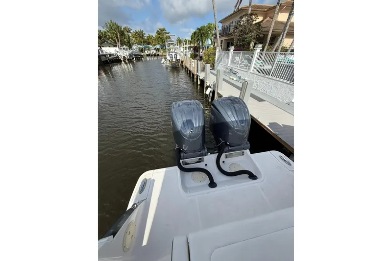 Slide: The Image of 2023 Chaparral 300 OSX boat with dual outboard engines docked by a waterfront property. - 12