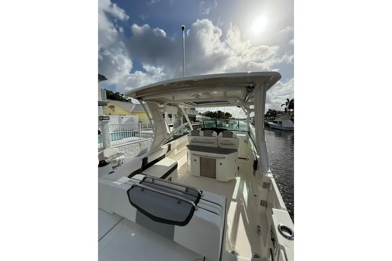 Slide: The Image of 2023 Chaparral 300 OSX boat interior with seating and helm, under a partly cloudy sky. - 14